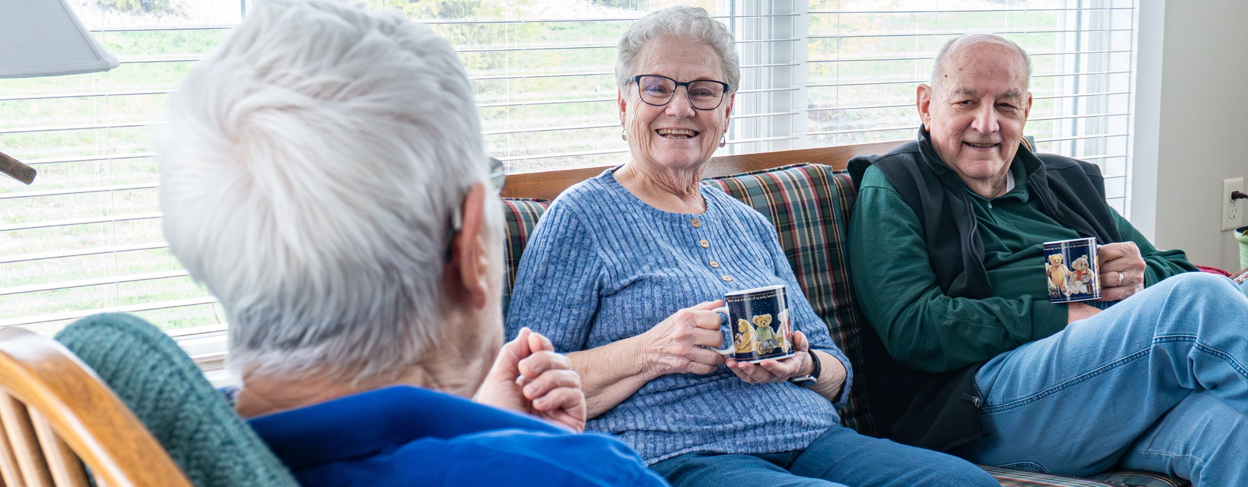 Senior couple seated on a sofa drinking coffee and chatting with a senior